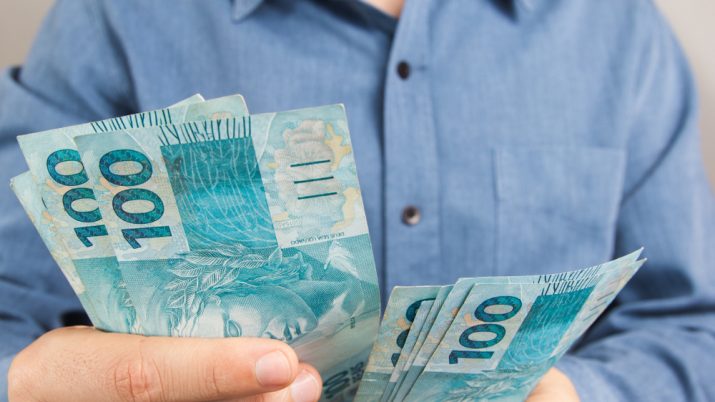 Pessoa conta notas de dinheiro de 100 reais