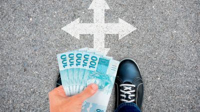 mão segura notas de cem reais enquanto define para onde ir