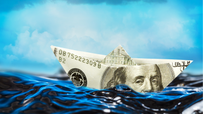 Barquinho feito com nota de dólar navegando no mar