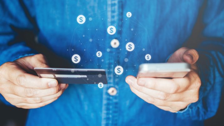 Homem segura cartão de crédito e celular