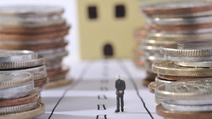 Imagem traz miniatura de idoso ao lado de pilhas de moedas