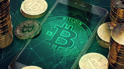 Imagem mostra celular com símbolo do bitcoin