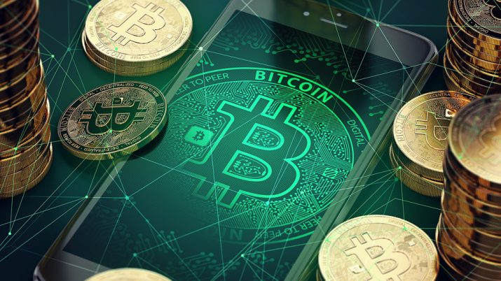 Imagem mostra celular com símbolo do bitcoin