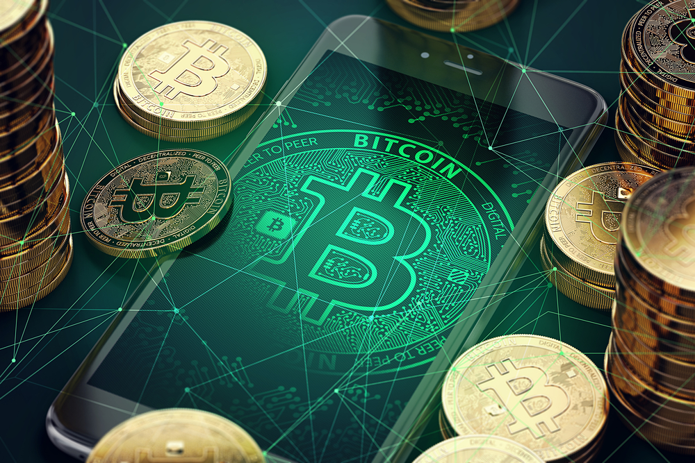 Imagem mostra celular com símbolo do bitcoin