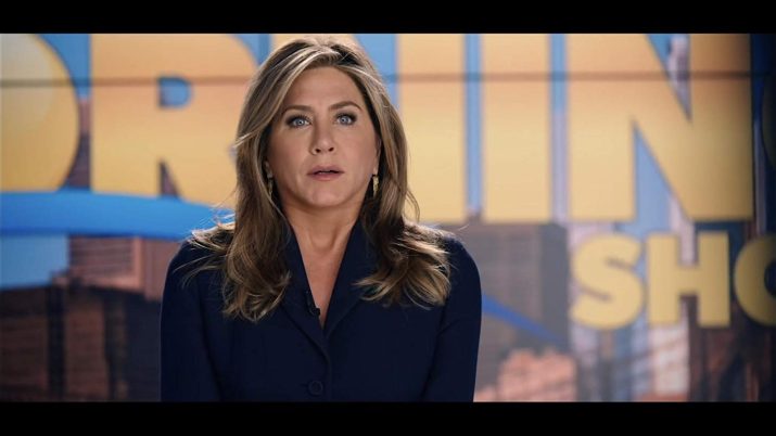 Jeniffer Aniston sentada em frente a um fundo de jornal