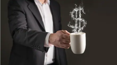 Homem segura xícara de café com fumaça em formato de cifrão