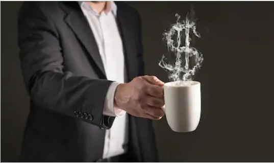 Homem segura xícara de café com fumaça em formato de cifrão
