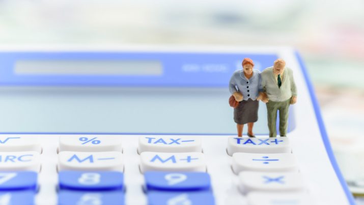 Bonequinhos de casal de idosos sobre calculadora