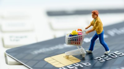 homem empurra carrinho de compras em cima de cartão de crédito