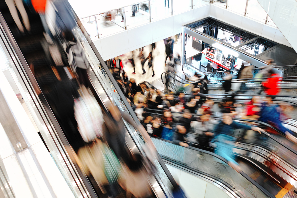 Escadas rolantes de shoppings centers com pessoas subindo e descendo | Iguatemi Multiplan MULT3 brMalls BRML3 Aliansce Allos ALSO3 Selic VISC11 XPML11