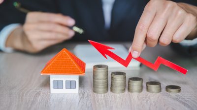 pilhas crescentes de moedas ao lado de imóvel, mostrando um movimento de alta