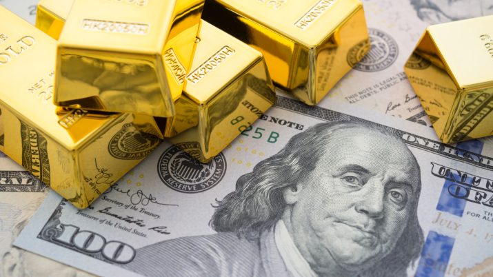 Imagem conceitual traz barras de ouro em cima de dólar