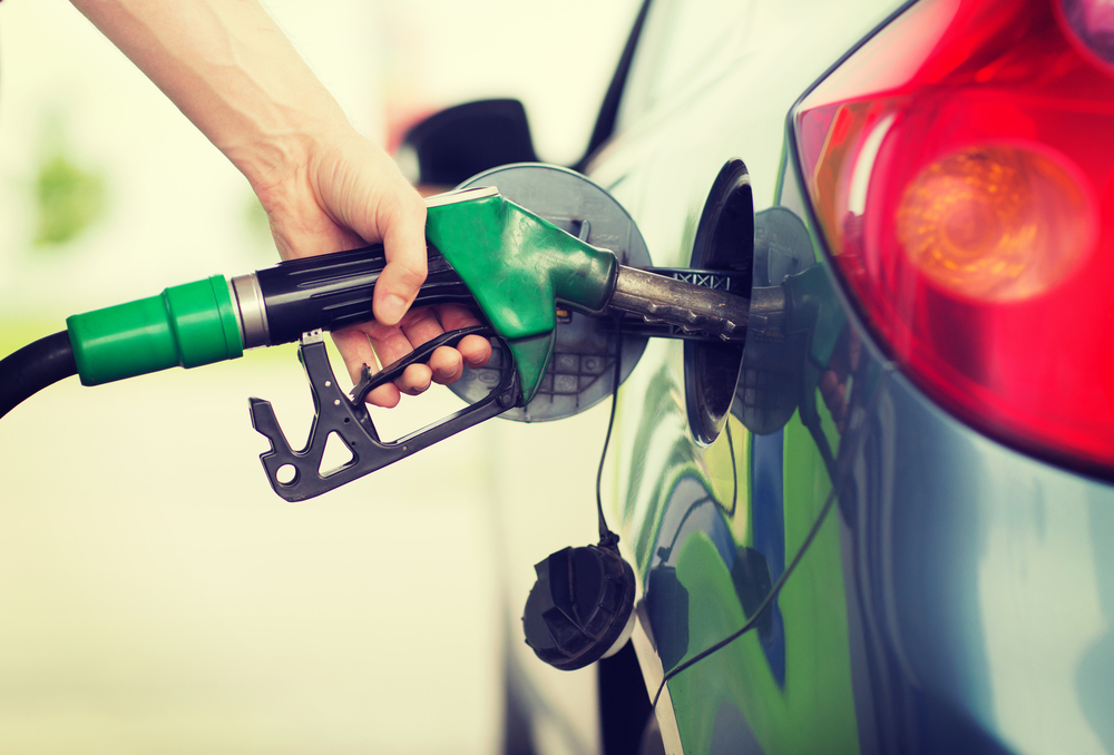 Mão abastecendo carro com etanol ou gasolina