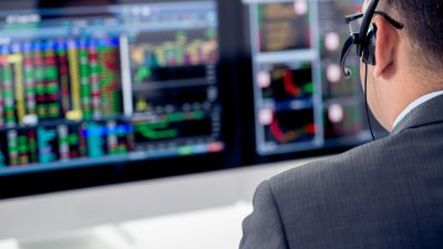 Foto mostra profissional olhando gráficos em terminal de mercado