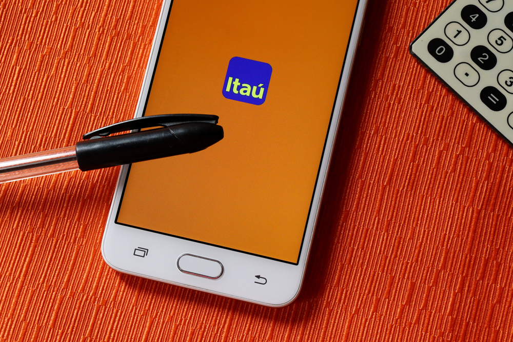 tela de celular com logotipo do itaú sob uma caneta