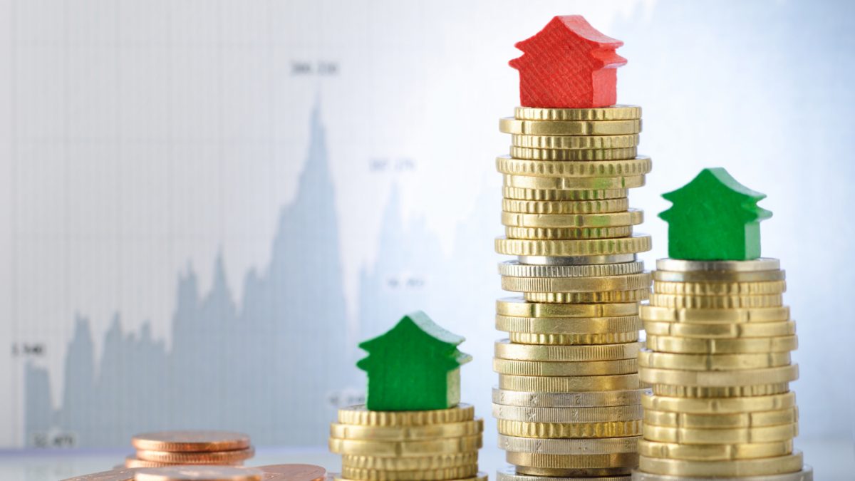 Casas e moedas em frente a um gráfico representando as cotas e os dividendos de fundos imobiliários