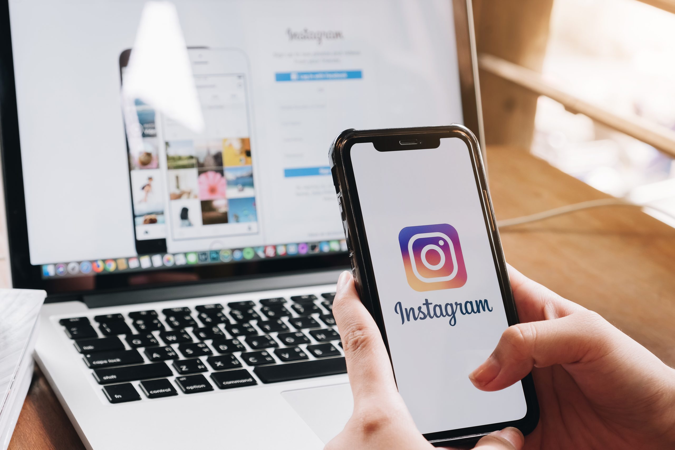 Imagem de celular com logo do Instagram na tela sendo segurado por duas mãos