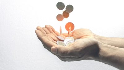 mão estendida enquanto moedas caem sobre as palmas | Dividendos
