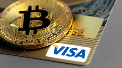 Moeda de bitcoin sobre um cartão da Visa