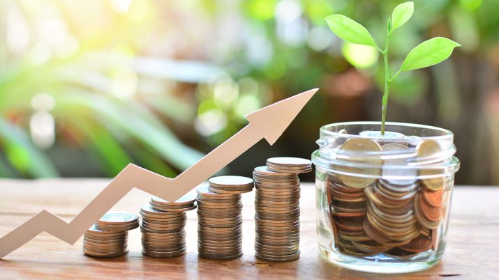 Moedas empilhadas,uma dos lado da outra, em tamanho ascendente, com montagem de seta indicando crescimento e um pote com moedas ao final (direita), simbolizando investimentos lucrativos