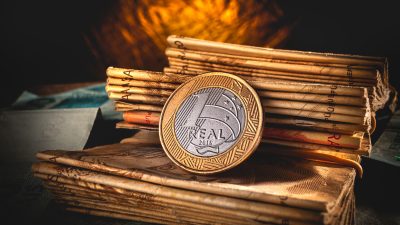 Moeda de 1 real colocada sobre uma pilha de moedas de 50 reais