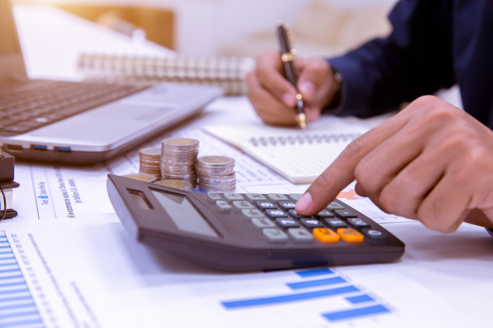 Midsection,Of,Businessman,Calculating,Tax,Using,Calculator,In,Office.
