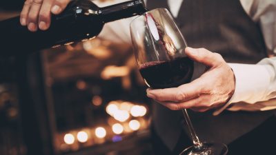 Close,Up.,Elegant,Waiter,Pours,Red,Wine,From,Bottle,Into