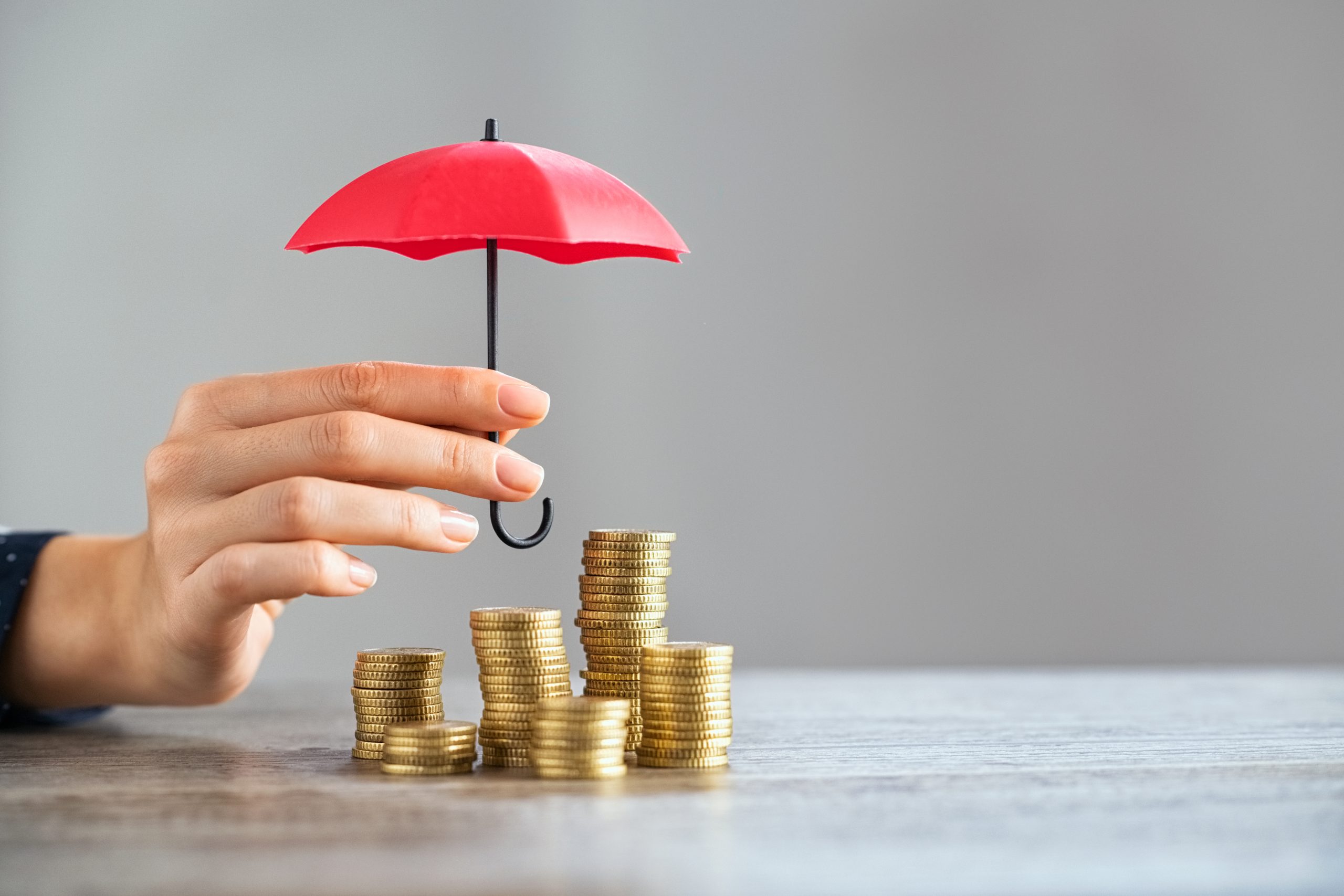 Imagem ilustrativa mostra guarda-chuva protegendo uma pilha de moedas, representando a inflação