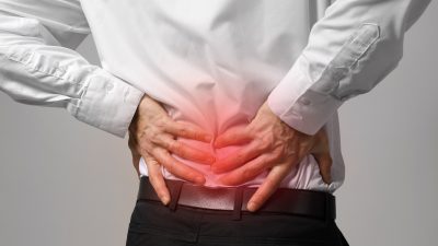 Man,Suffering,From,Back,Ache,On,Gray,Background.,Health,Care