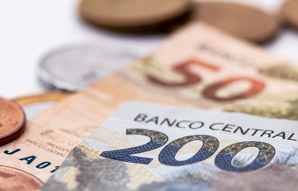 Notas de 50 e 200 reais + moedas expostas em uma mesa