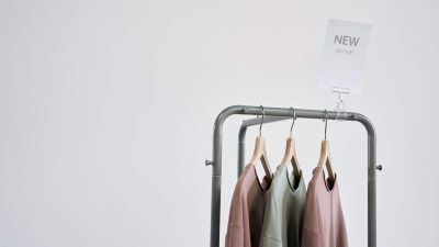Em frente a um fundo branco, três moletons coloridos estão pendurados em uma arara cinza. | Marisa