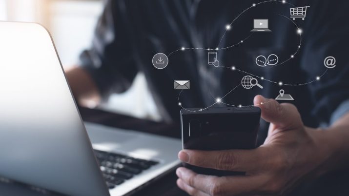 Tecnologia: Homem segurando um celular rodeado de ícones de e-mail, download, computador, pesquisa na internet, bate-papo, localização e mais