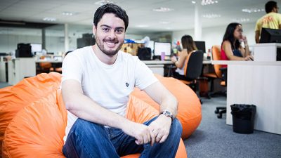 Victor Noda, CEO da Mobly, sentado em um pufe laranja no escritório