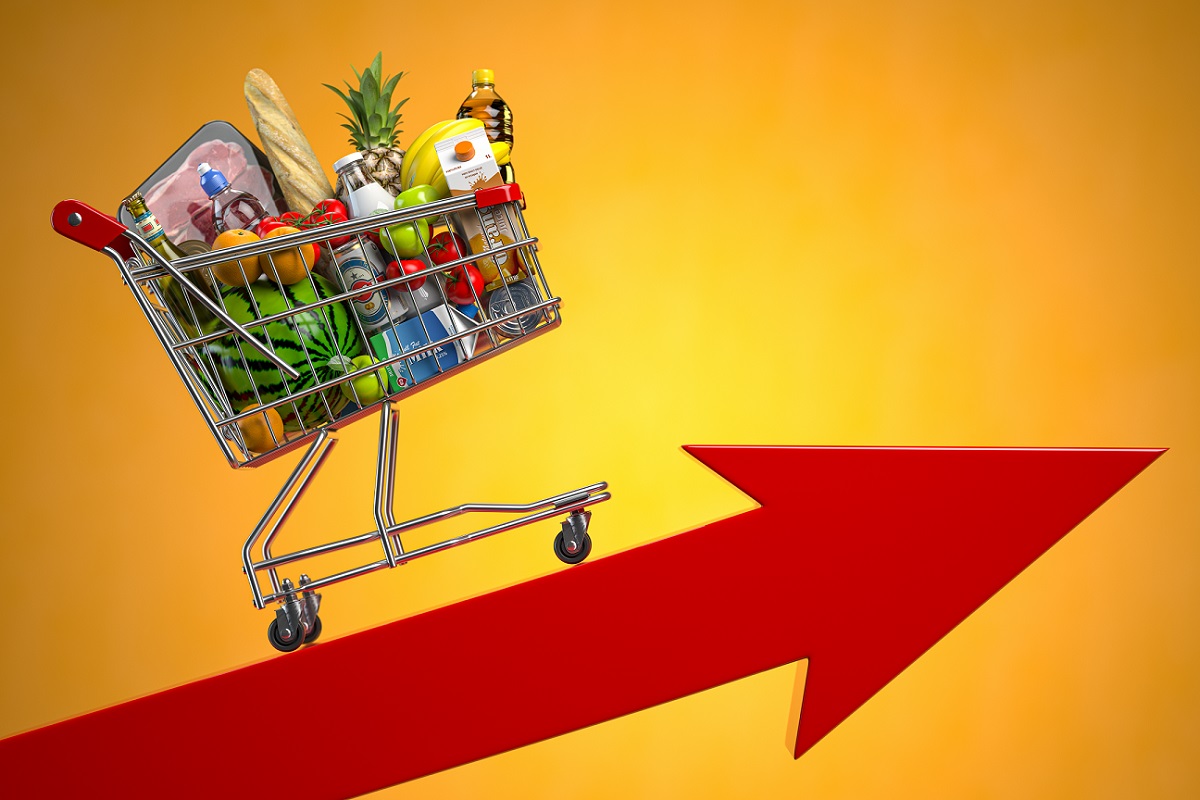 Um carrinho de mercado cheio de compras está em cima de uma seta vermelha apontando para cima
