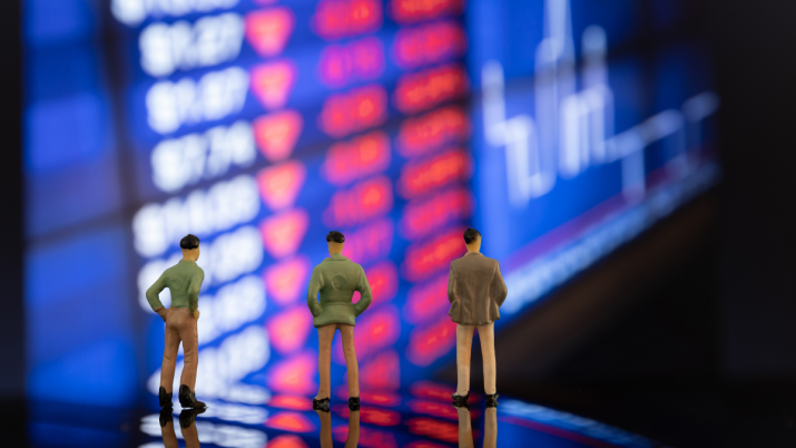 bonecos em primeiro plano observam gráfico com cotações de mercado ao fundo | Ibovespa, ações, Petrobras, PETR4