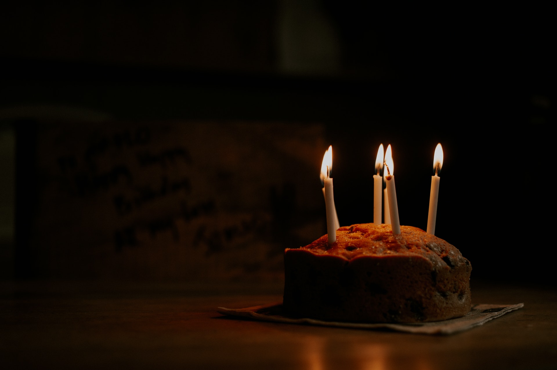 Bolo com quatro velas acessas em uma sala escura