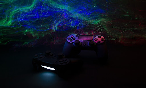 O fundo é verde e azul, com um controle preto de Playstation na frente.