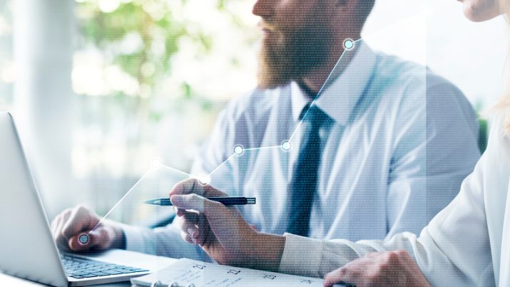 Imagem mostra homem de camisa e gravata, com barba, mexendo no computador, representando um assessor de investimentos