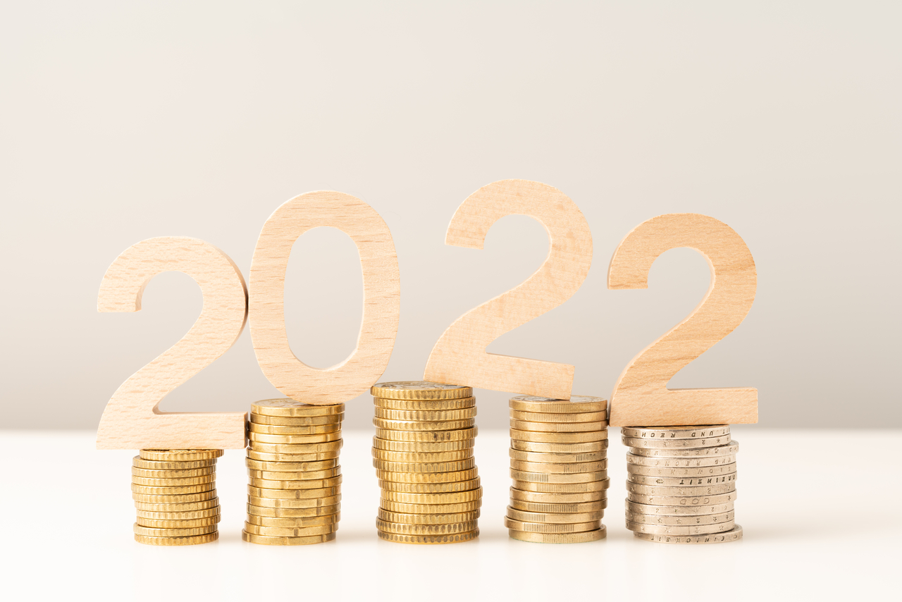 Números de madeira formando "2022" sobre pilhas de moedas
