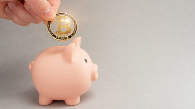 Moeda fictícia de Bitcoin sendo colocar em um porquinho
