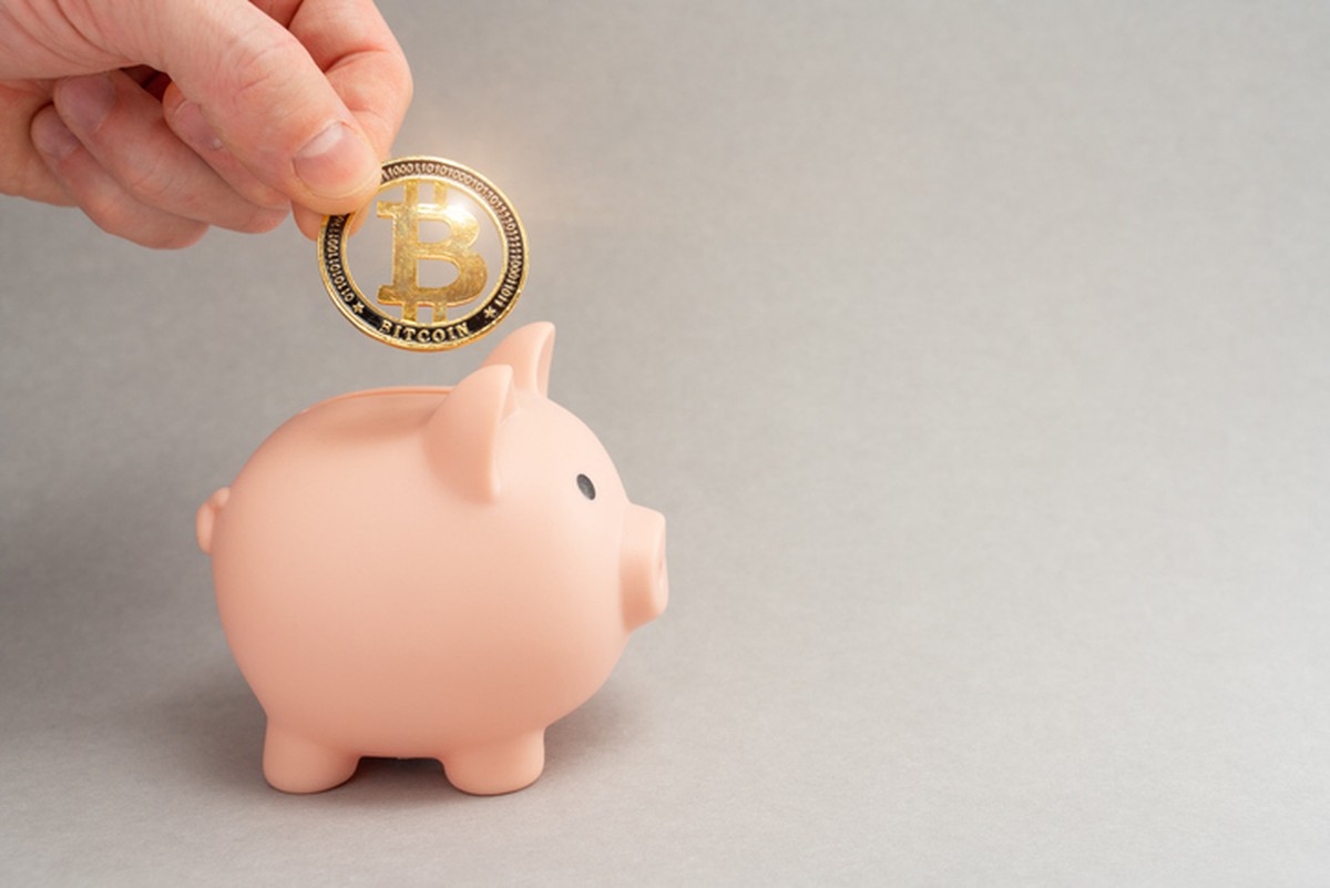 Moeda fictícia de Bitcoin sendo colocar em um porquinho