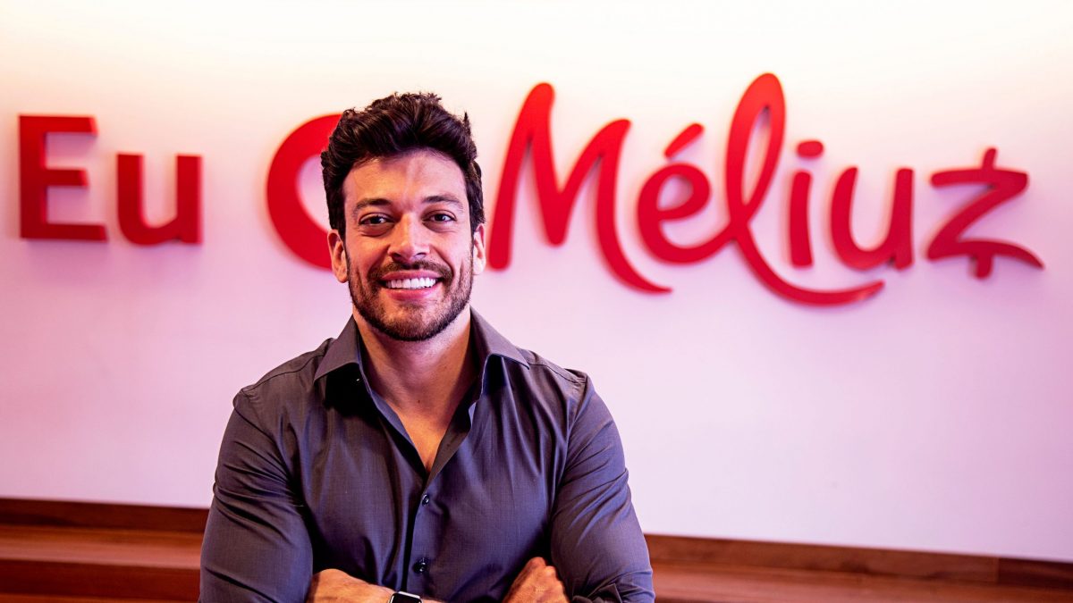 Israel Salmen, fundador do Méliuz, em frente ao logo da empresa