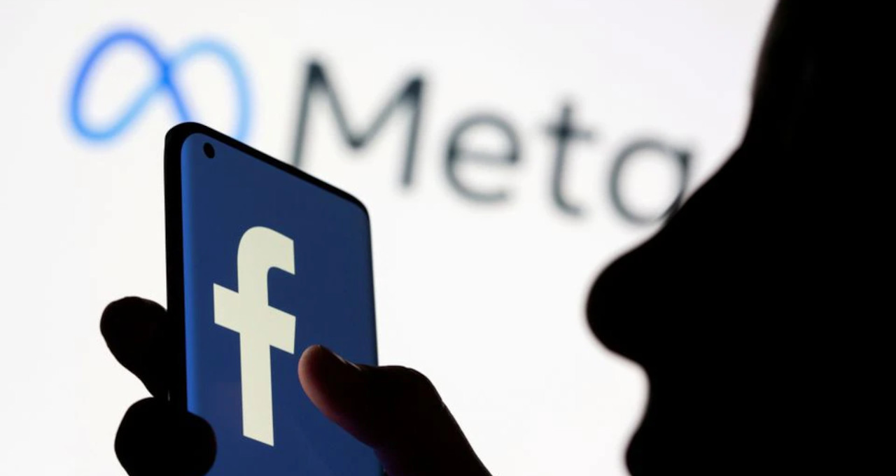 Imagem de celular com logotipo do Facebook e da Meta ao fundo