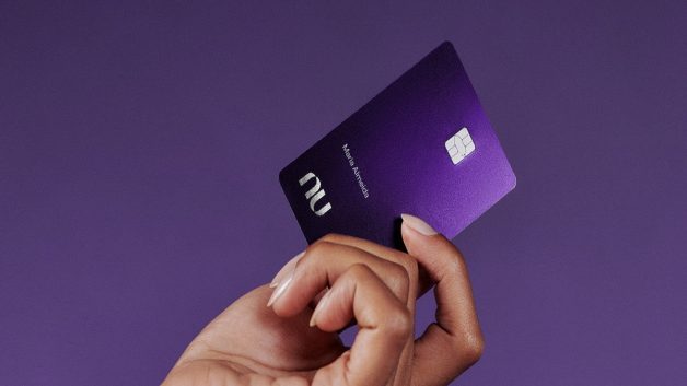 Mão segurando cartão roxo do Nubank