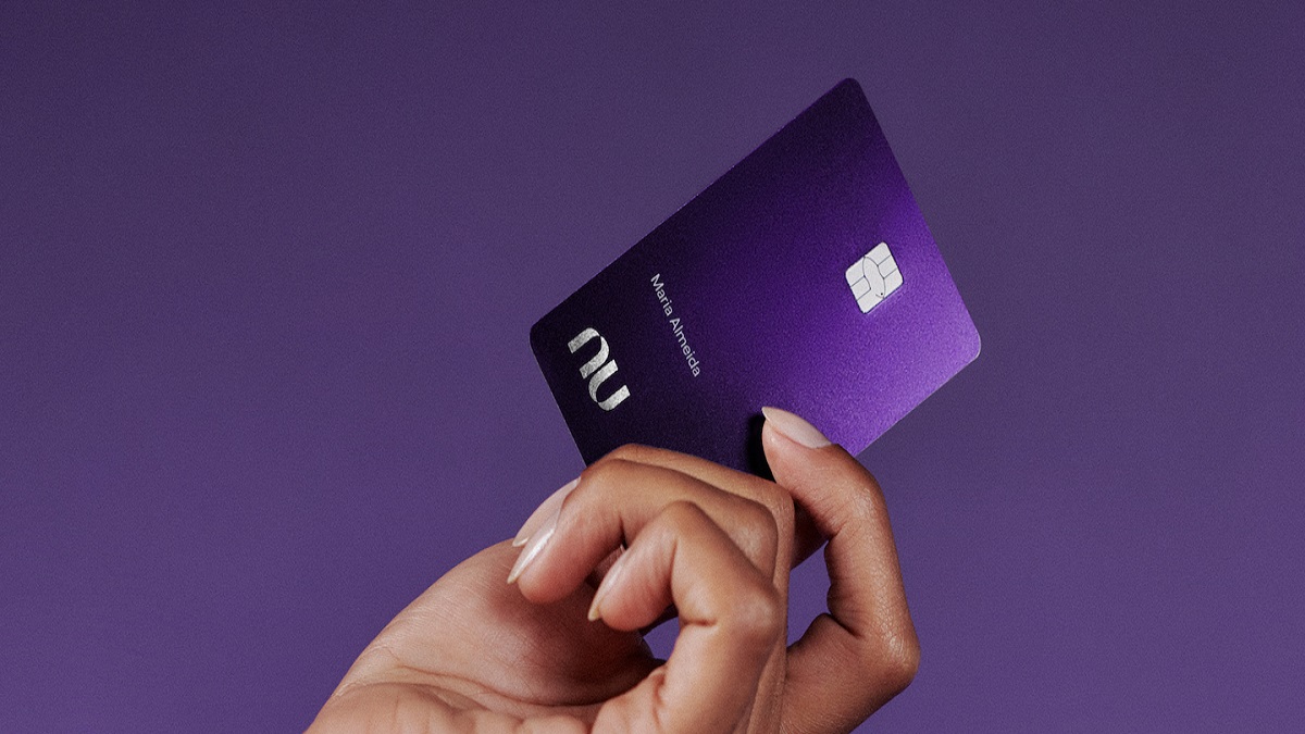 Mão segurando cartão roxo do Nubank