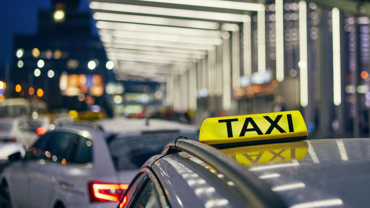 Iluminação sinal de táxi no teto do carro contra terminal do aeroporto à noite