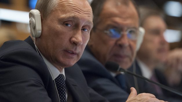 Presidente russo, Vladimir Putin, sentado em uma mesa com fone ouvido