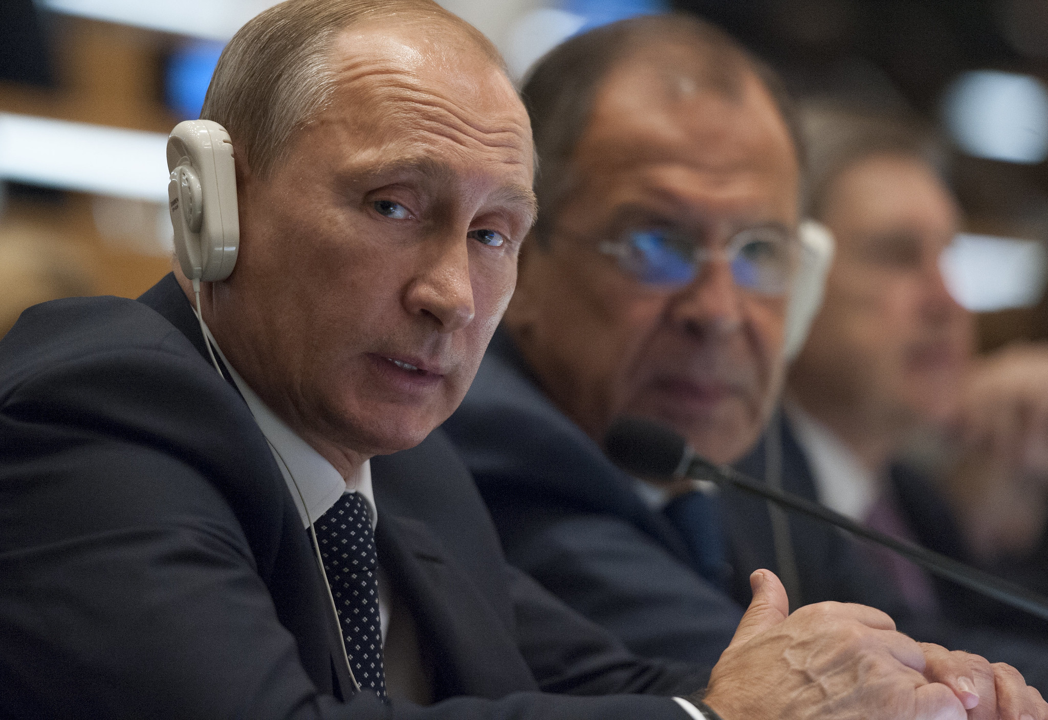 Presidente russo, Vladimir Putin, sentado em uma mesa com fone ouvido
