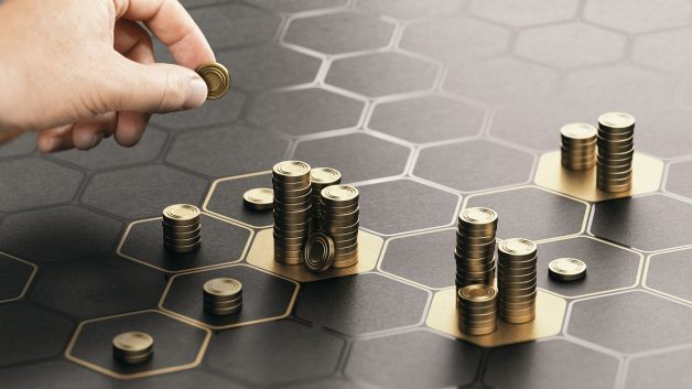 Imagem mostrando uma mão depositando moedas sobre um tabuleiro preto; representa o pagamento de proventos aos acionistas, como dividendos e juros sobre o capital Próprio (JCP) | Dividendos, fundos imobiliários, CVM, Maxi Renda, MXRF11 Fundo imobiliário TRXF11