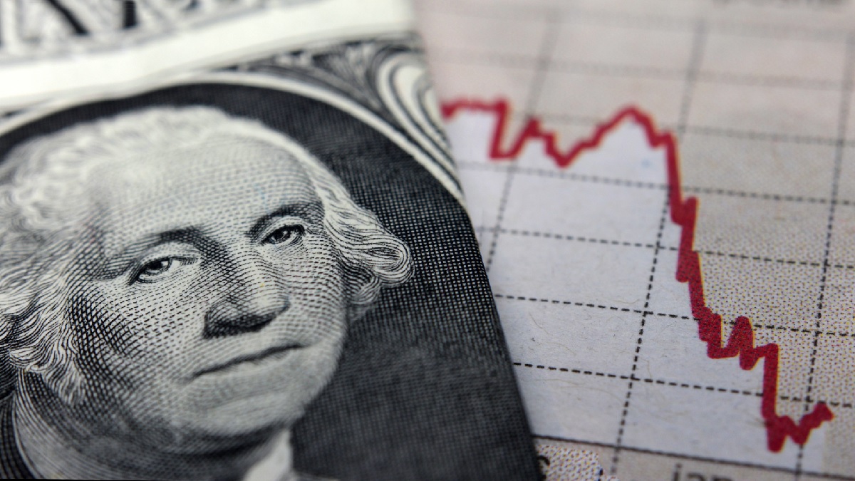 Imagem mostrando uma cédula de dólar no primeiro plano e um gráfico indicando queda ao fundo; indica a correlação entre o câmbio e a bolsa